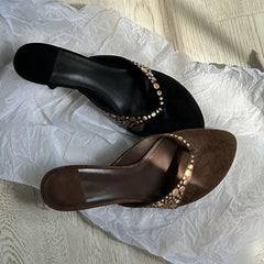 Overhead view of black and brown studded thong kitten heel sandals