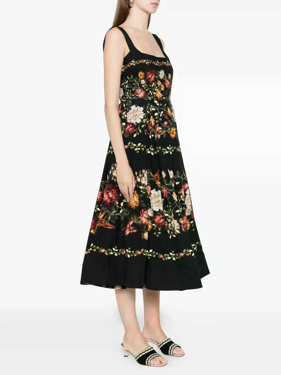 Side view of a black floral print square neck sleeveless A-line midi dress with a gathered hem worn by a model.