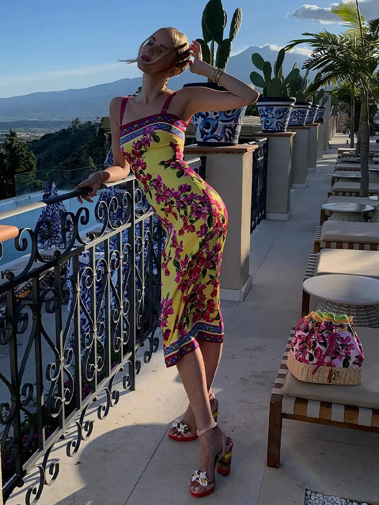 Woman in a colorful dress standing on a balcony with scenic views and cacti.