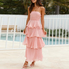 Woman wearing a pink strapless dress with ruffled layers by a poolside.