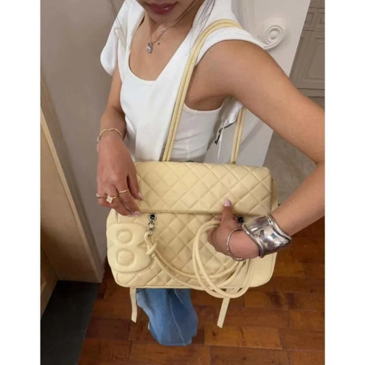 Quilted satchel shoulder bag with a decorative charm.