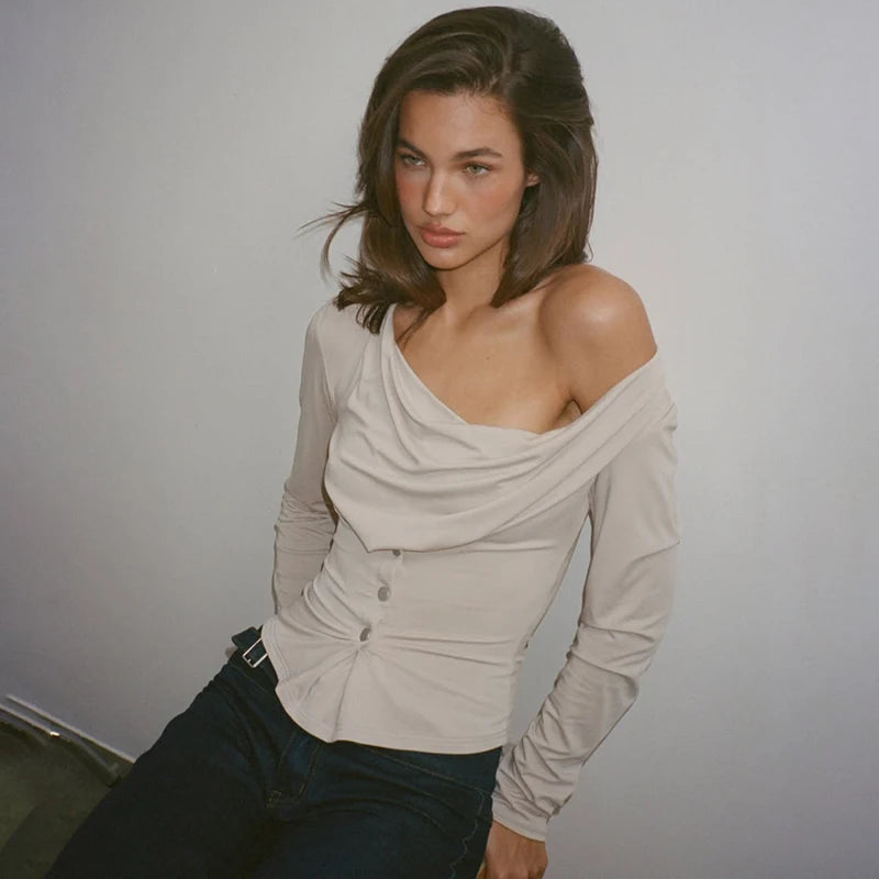 Woman wearing a beige off-shoulder top against a plain background