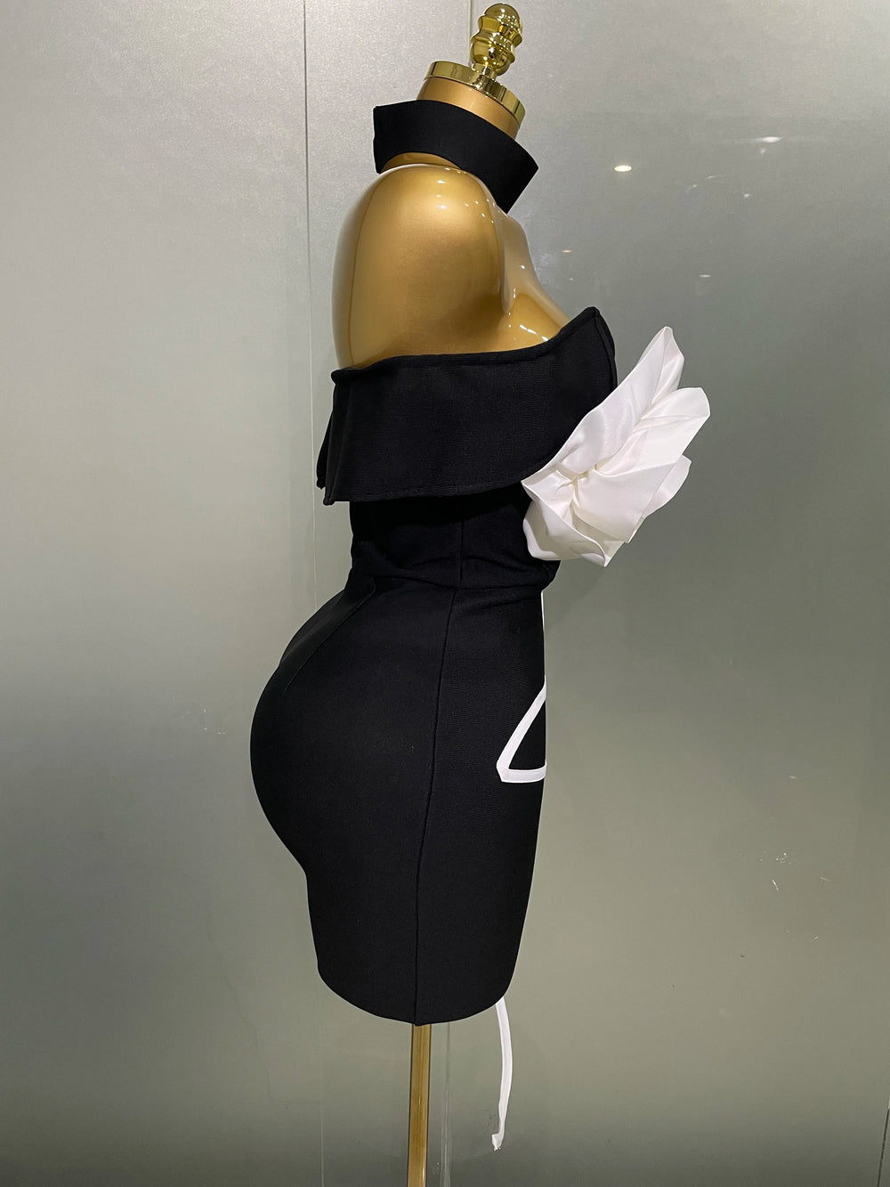 Black off-shoulder dress with white gloves on a mannequin against a neutral background