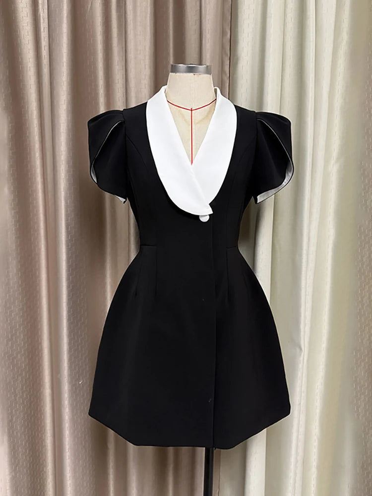Black dress with white collar on a mannequin against a beige curtain background