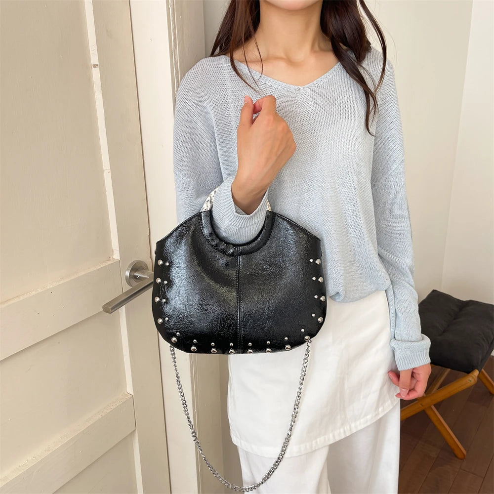 Model carrying a black studded faux leather hobo bag.