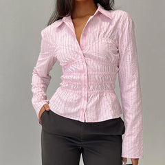 Person wearing a pink checkered shirt with long sleeves against a gray background