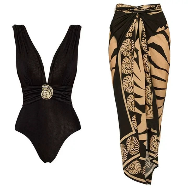 Black textured one-piece swimsuit with gold-tone embellishment and a matching black wrap skirt with a seashell-inspired print.