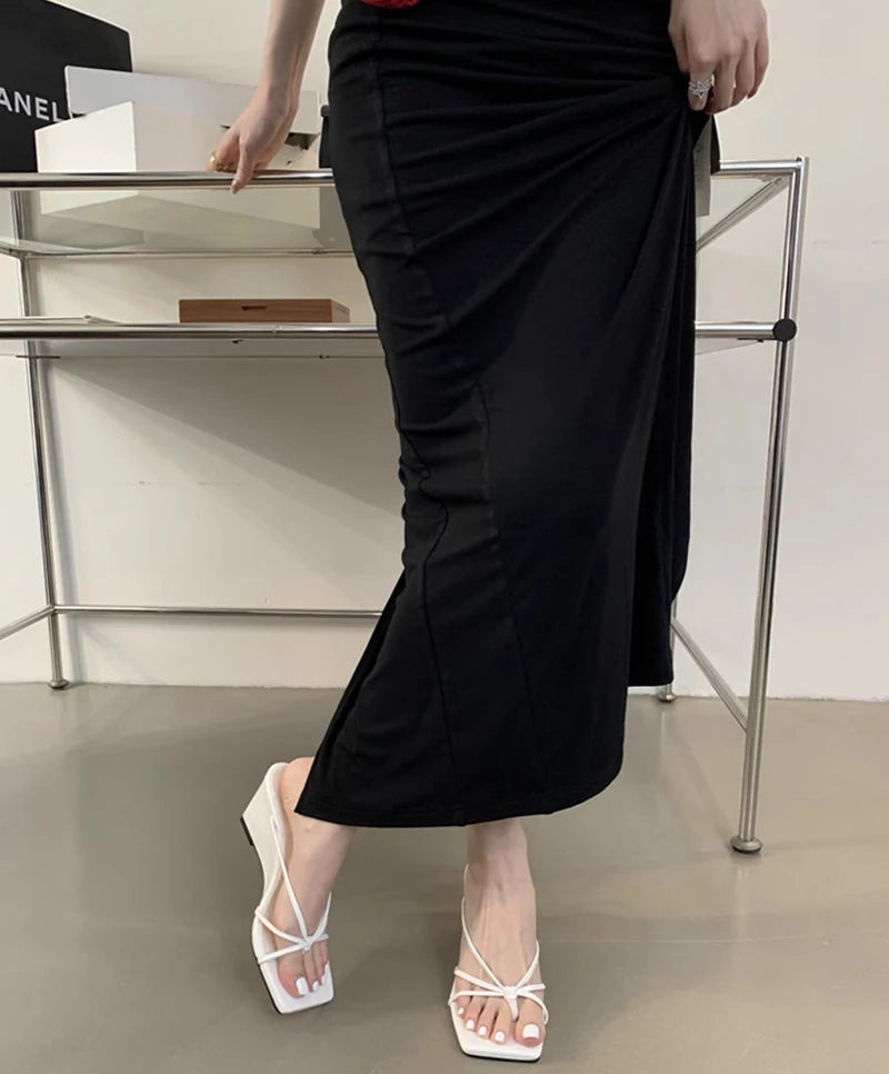 Person wearing a black dress with a slit, standing in front of a glass display case.