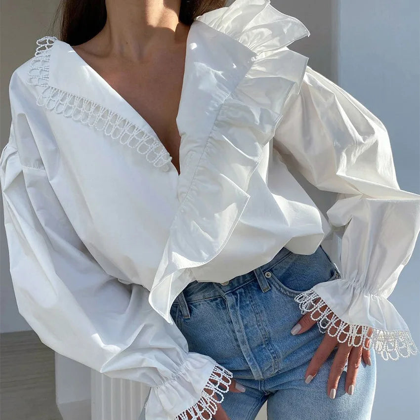 White blouse with lace details worn by a person, standing against a neutral background