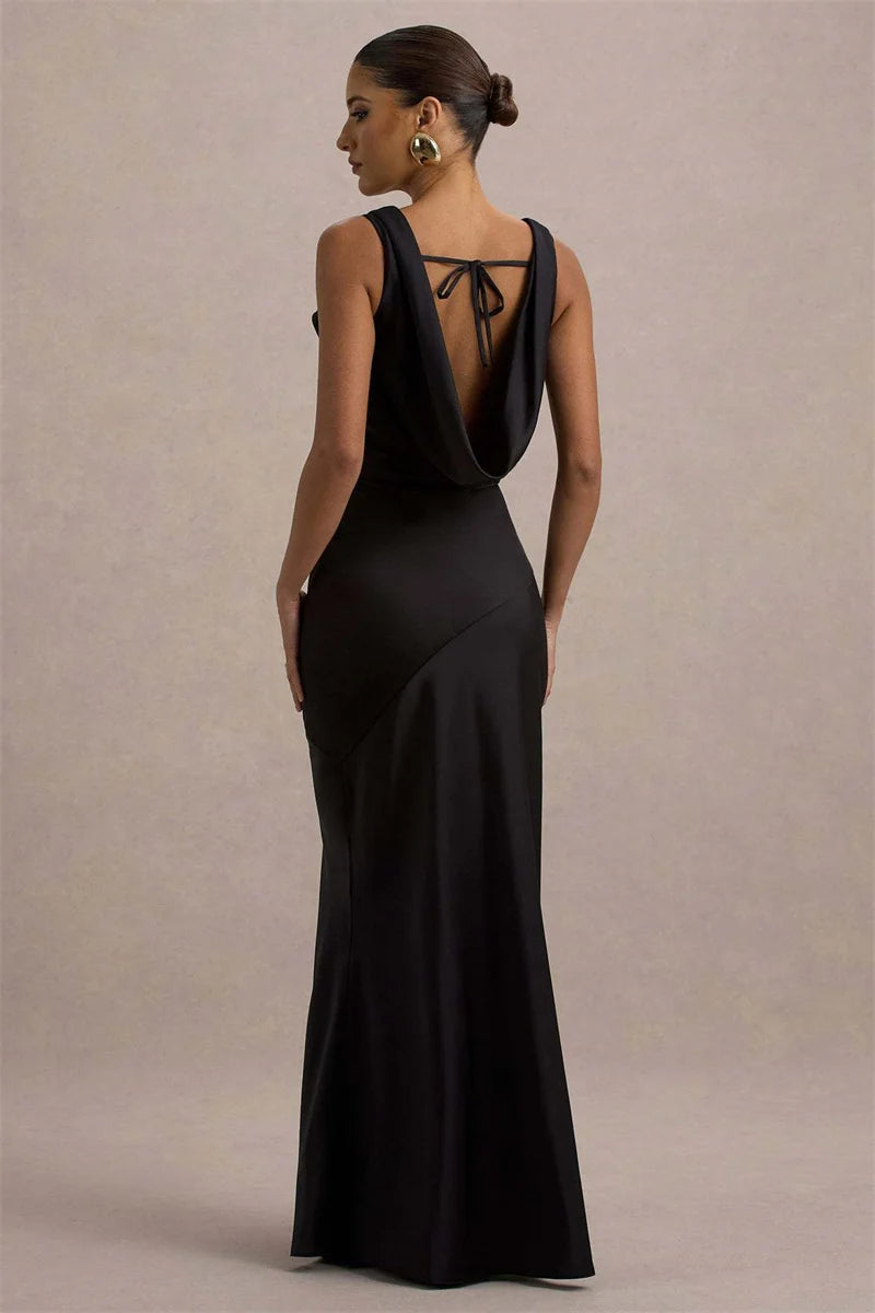 Woman wearing a black evening gown with a deep neckline against a beige background