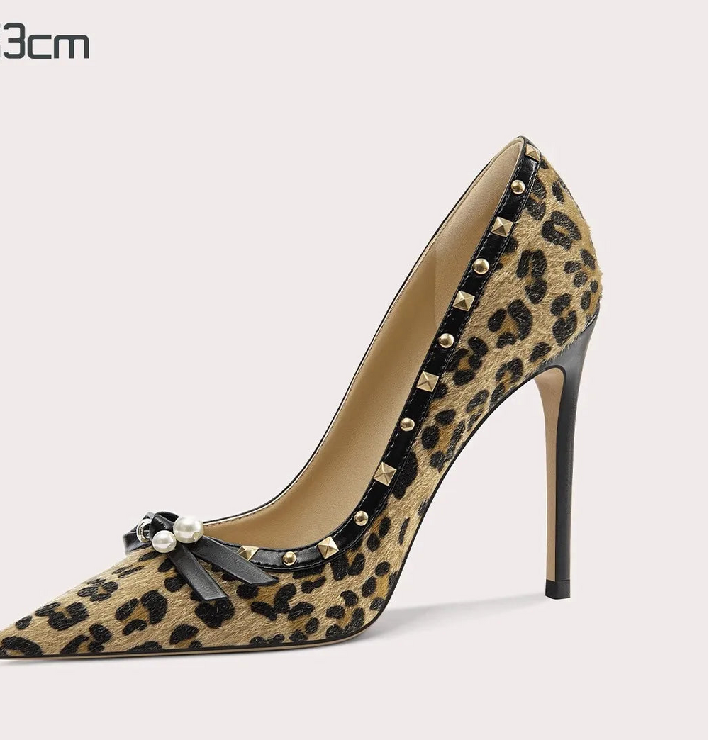 Leopard print high-heeled shoe with studded details on a light gray background