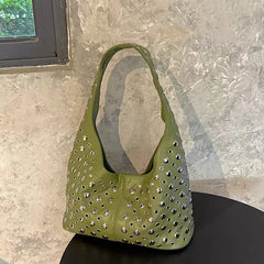 Green handbag with studs on a marble surface
