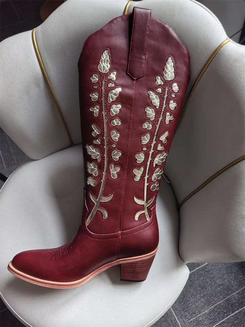 Maroon cowboy boot with white embroidery on a white chair