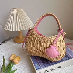Wicker handbag with pink accents on a surface with a lamp and flowers in the background