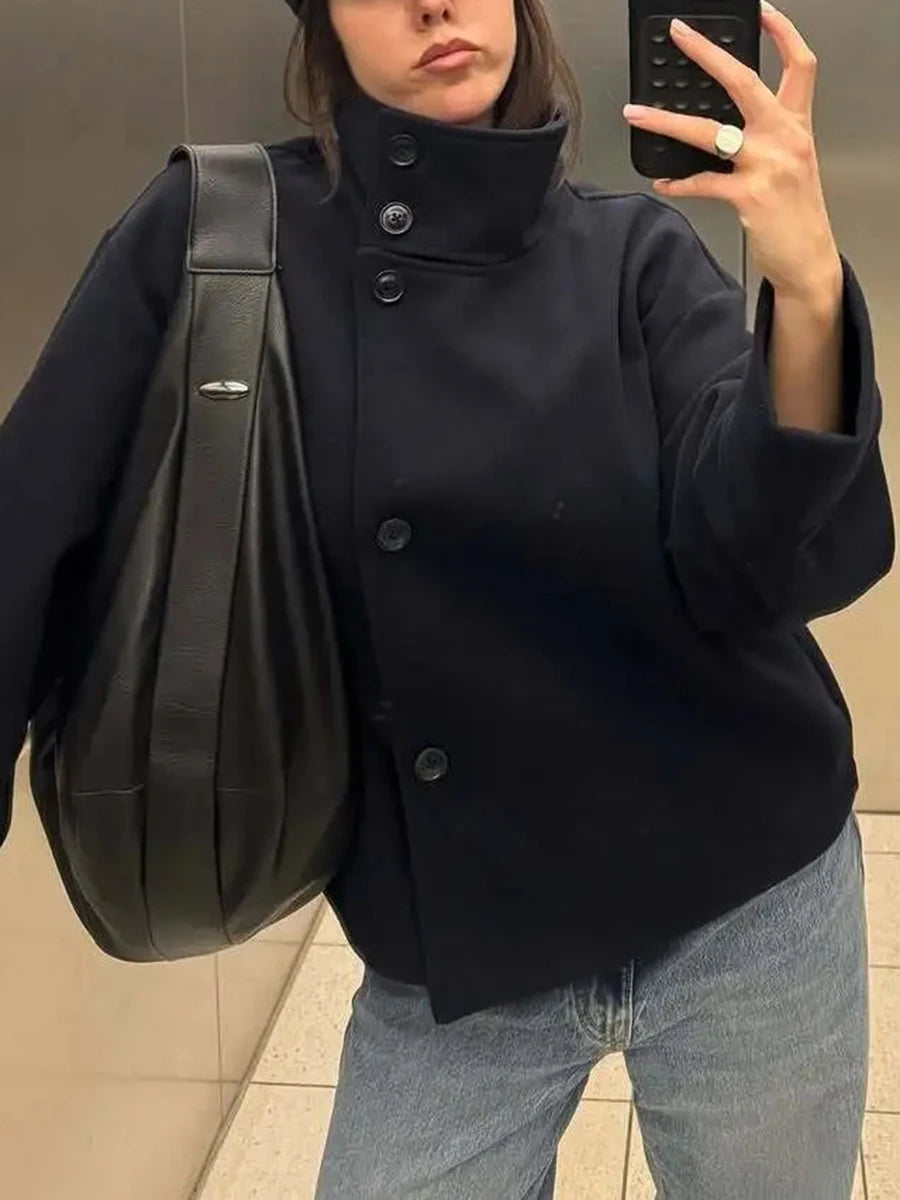 Close-up of the high neck and button details on a black cropped jacket.
