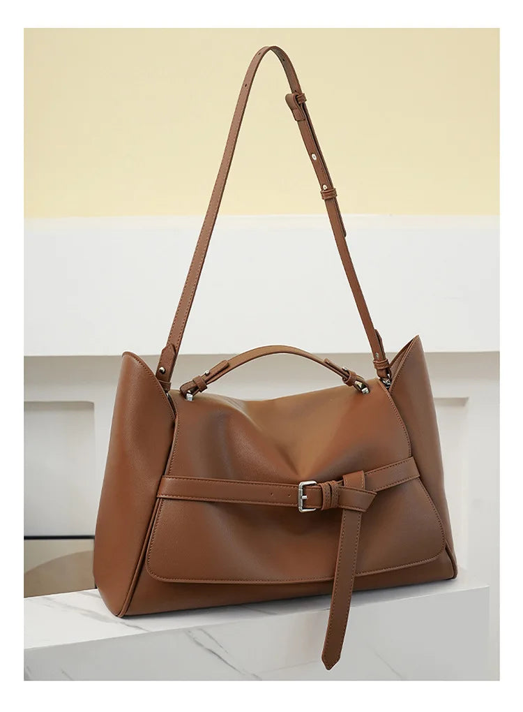 Brown leather handbag with a strap on a light background