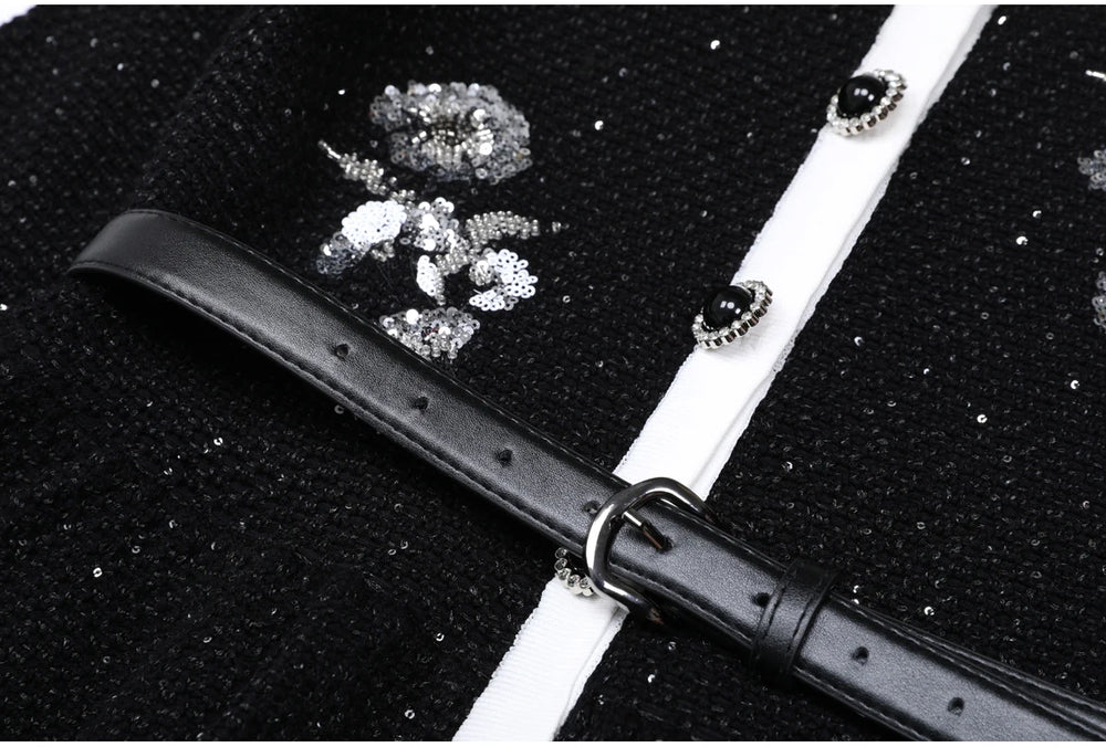 Close-up of the belt and sequin embroidery on a black knit cardigan.