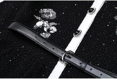 Close-up of the belt and sequin embroidery on a black knit cardigan.