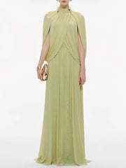 Woman wearing a light green evening gown with a cape on a white background