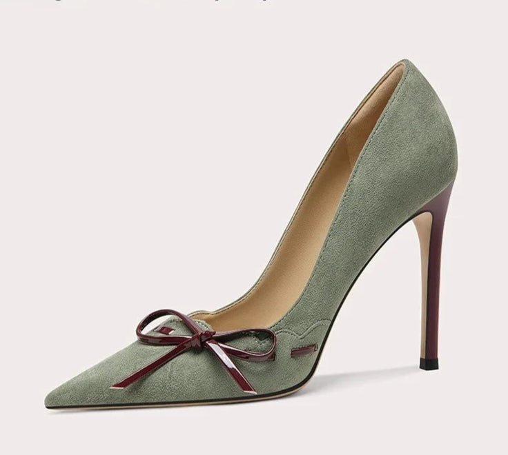 Green high-heeled shoe with a bow on a light gray background