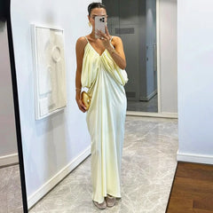 Woman in a light-colored dress taking a mirror selfie in a room with a painting on the wall.