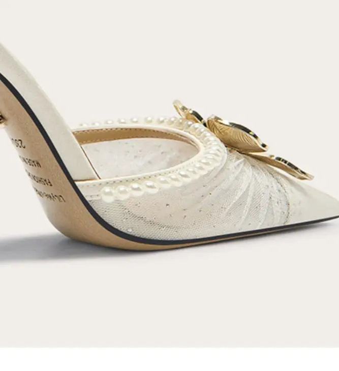 White high-heeled shoe with decorative elements on a light gray background