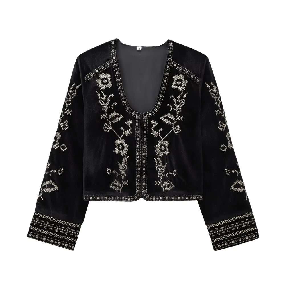 Flat lay of a black velvet cropped jacket with silver embroidery.