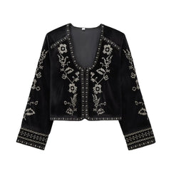 Flat lay of a black velvet cropped jacket with silver embroidery.