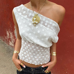 Person wearing a white polka dot top with a red background