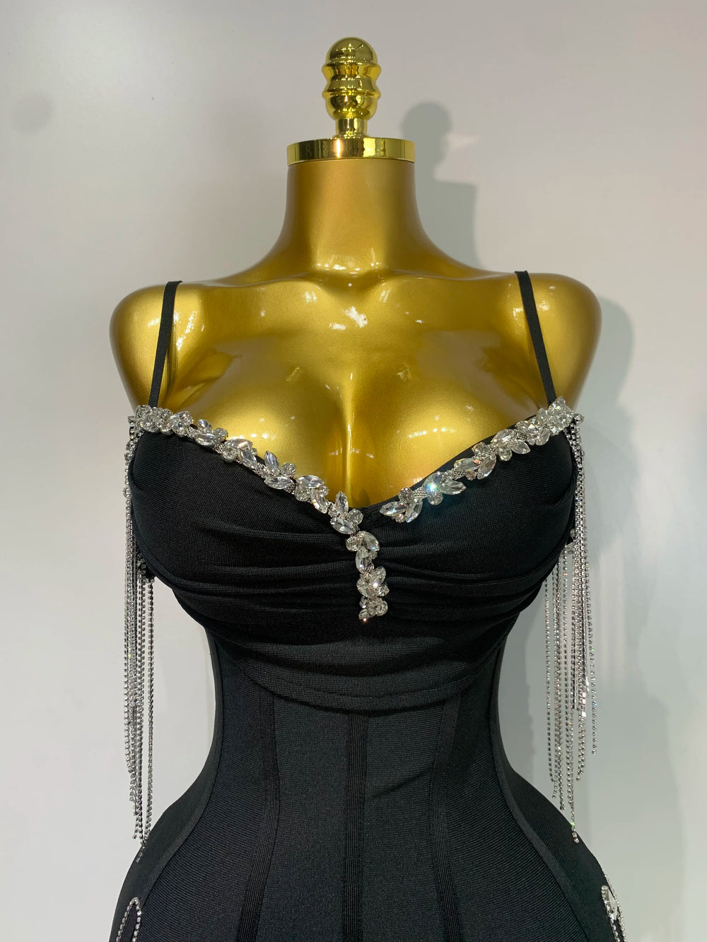 Black evening gown with crystal embellishments on a gold mannequin against a white background