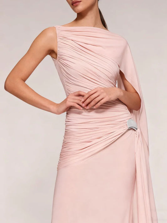 Pink one-shoulder dress with a silver brooch on a plain background