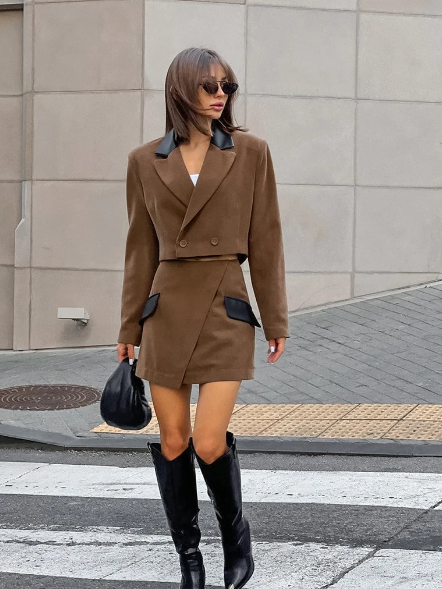 Woman in a brown outfit with black accents standing on a street.