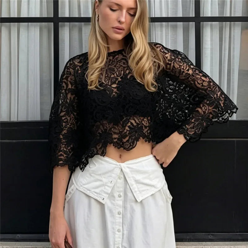 Black cropped lace top with batwing sleeves worn with a white skirt.