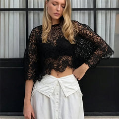 Black cropped lace top with batwing sleeves worn with a white skirt.
