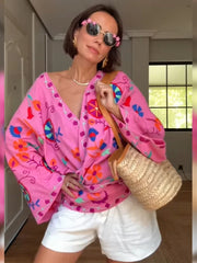 Woman wearing a pink embroidered kimono jacket with white shorts.