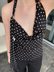 Person wearing a black polka dot dress with a deep neckline.