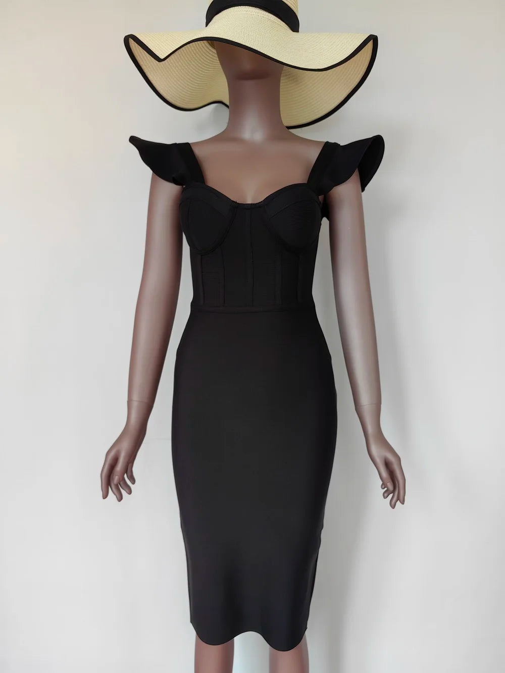 Mannequin wearing a black dress with ruffled shoulders and a wide-brimmed hat