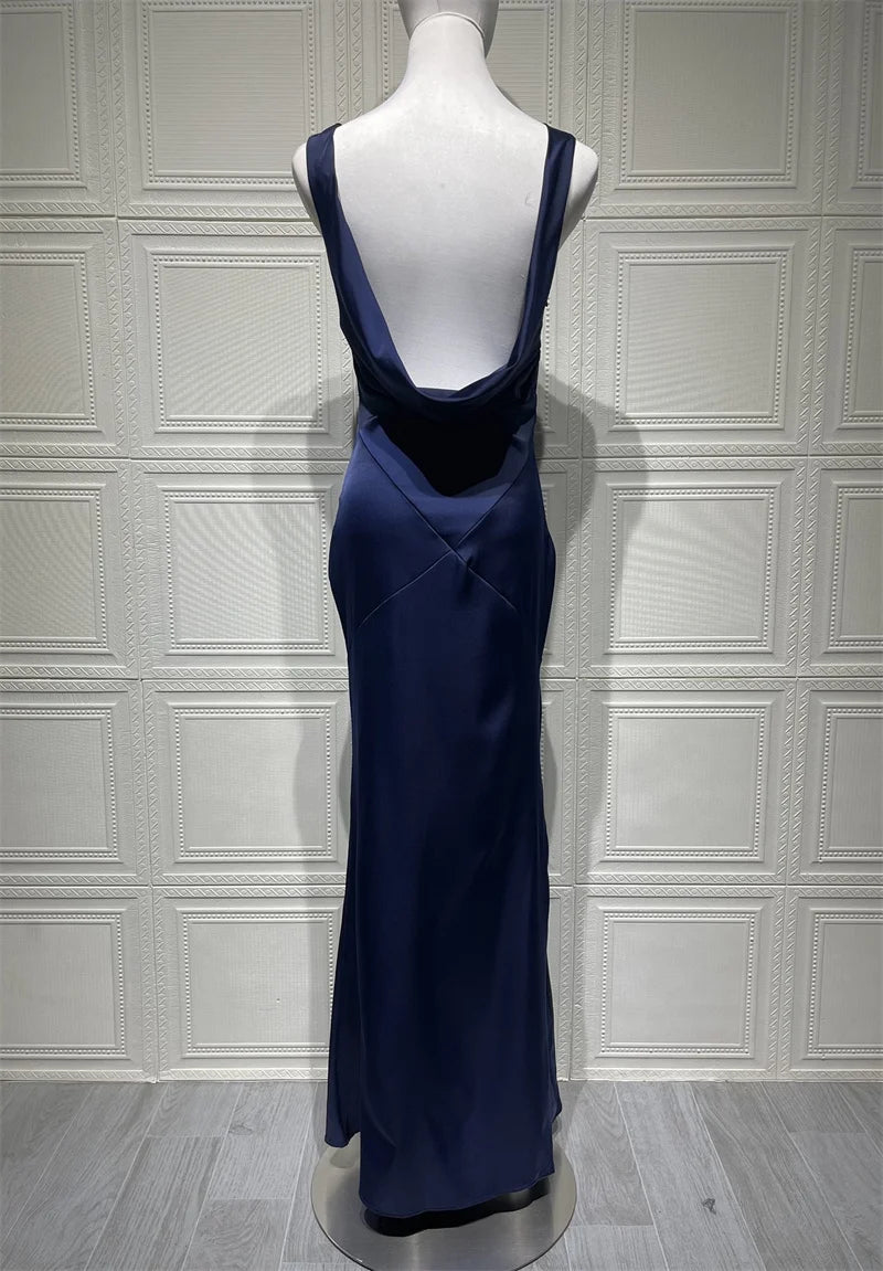 Navy blue evening gown on a mannequin against a white paneled wall.