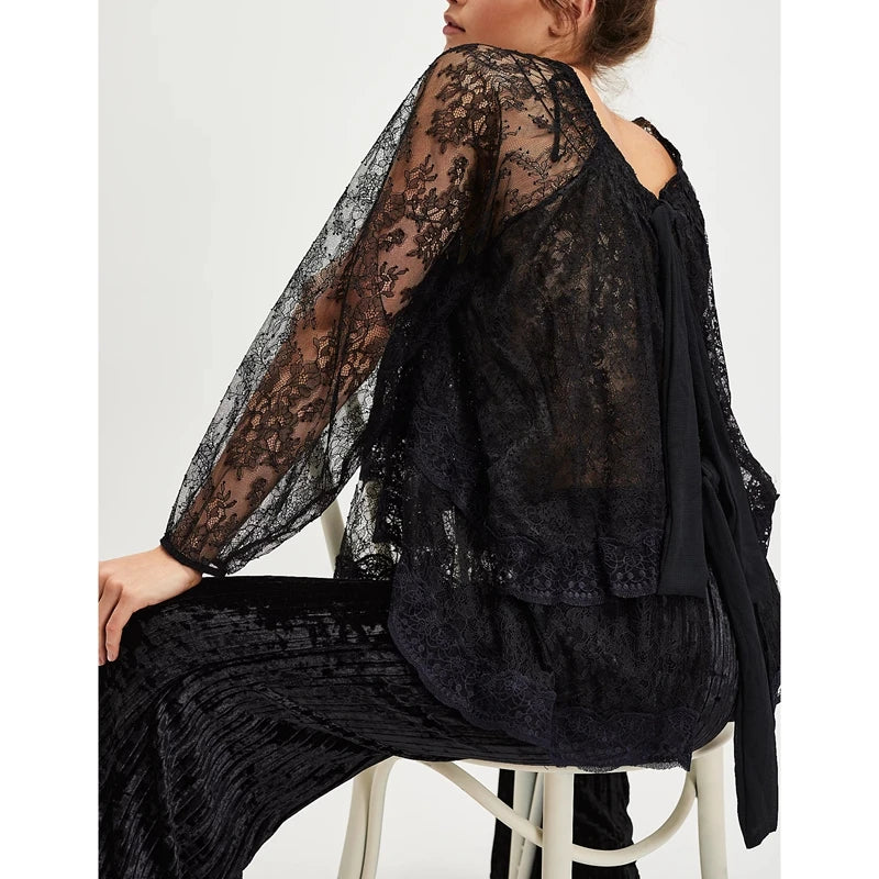 Person wearing a black lace outfit sitting on a white stool against a white background