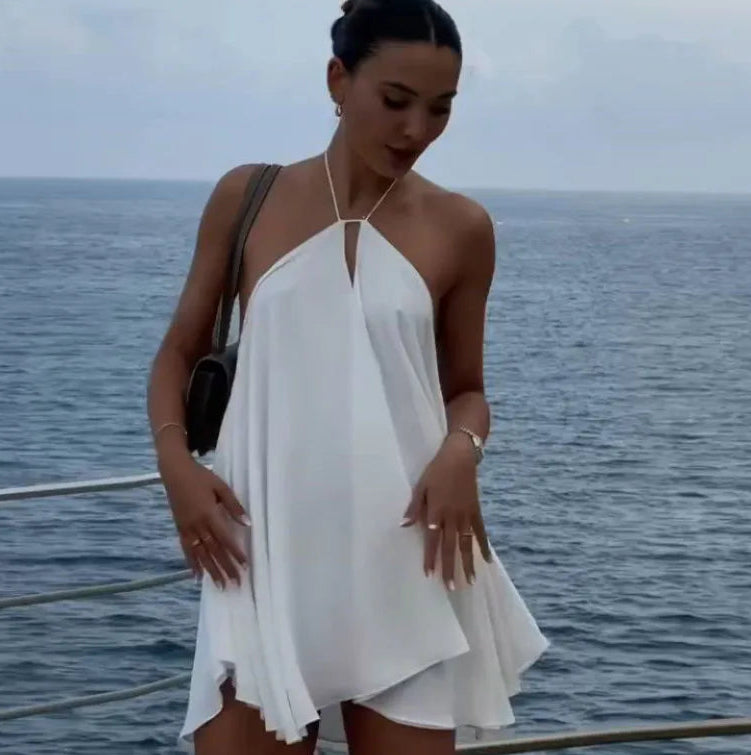 Woman in a white dress standing on a boat with ocean in the background