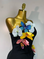 Side view of a black midi dress with floral accents and slit