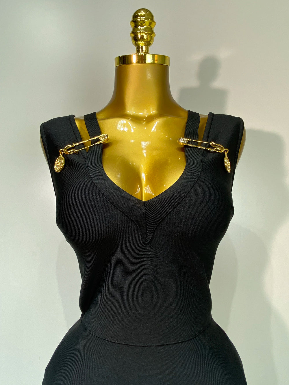 Black sleeveless top with gold accents on a mannequin against a plain background