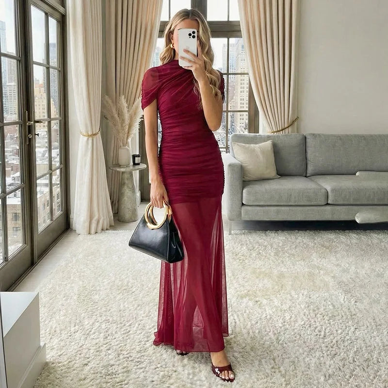 Woman in a burgundy dress taking a mirror selfie in a stylish room.