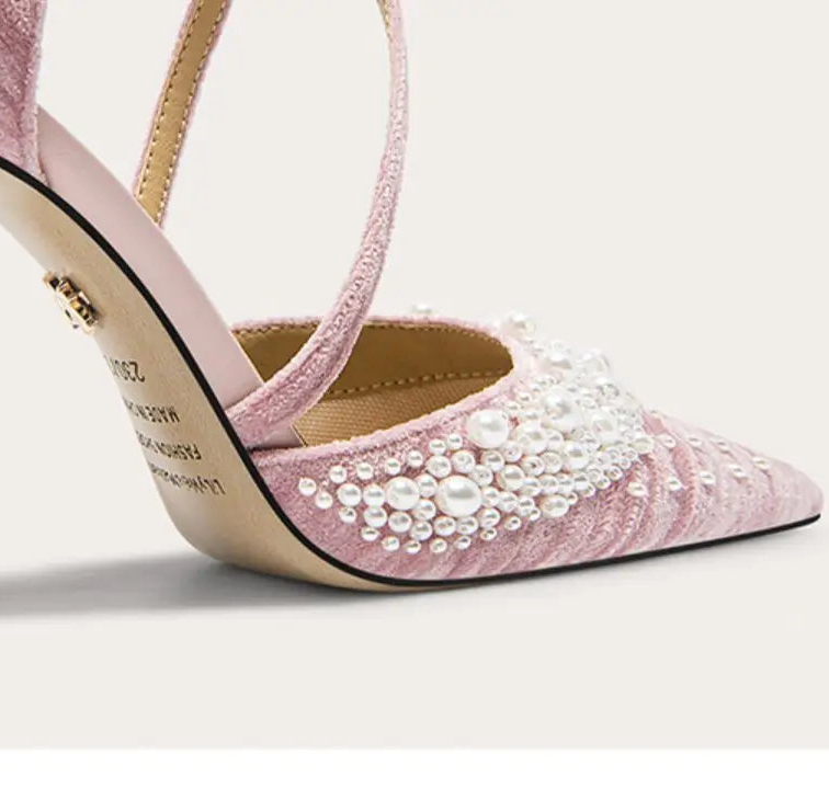 Pink high-heeled shoe with pearl embellishments on a light background