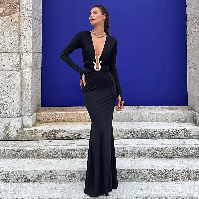 Woman in a black evening gown standing on stone steps with a blue wall behind her