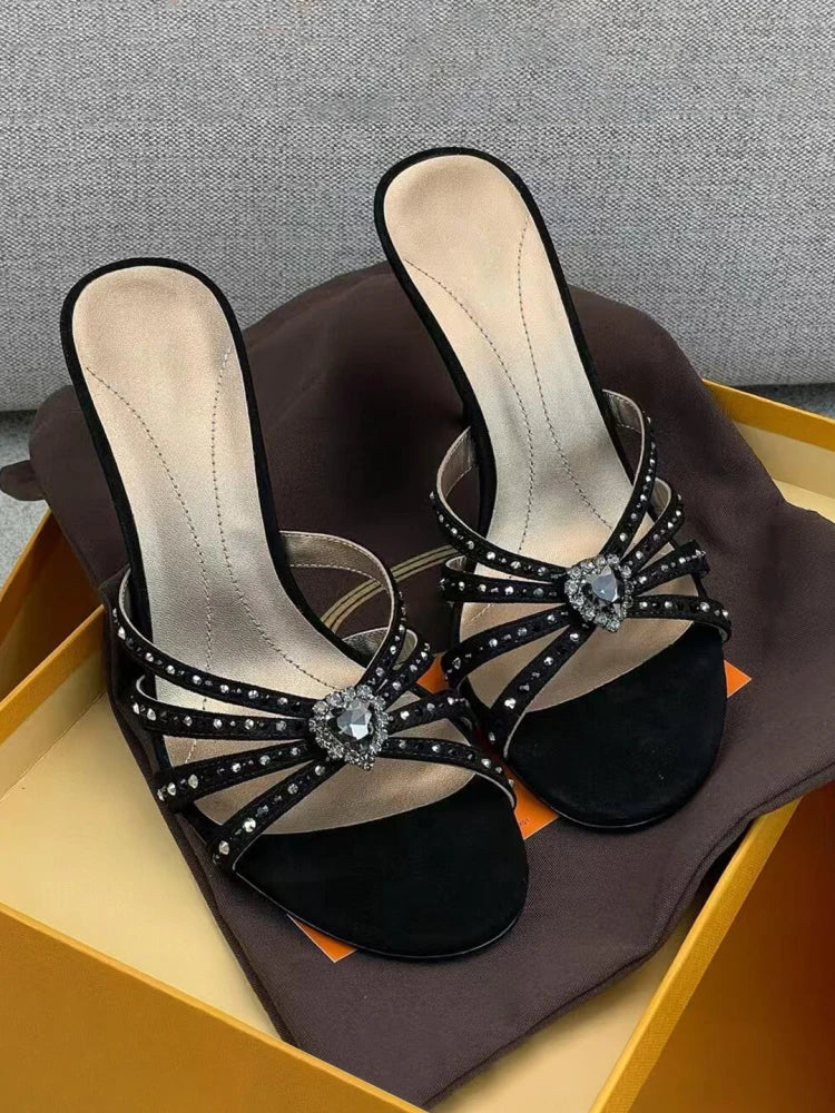 Black embellished stiletto heeled sandals displayed in a shoe box.