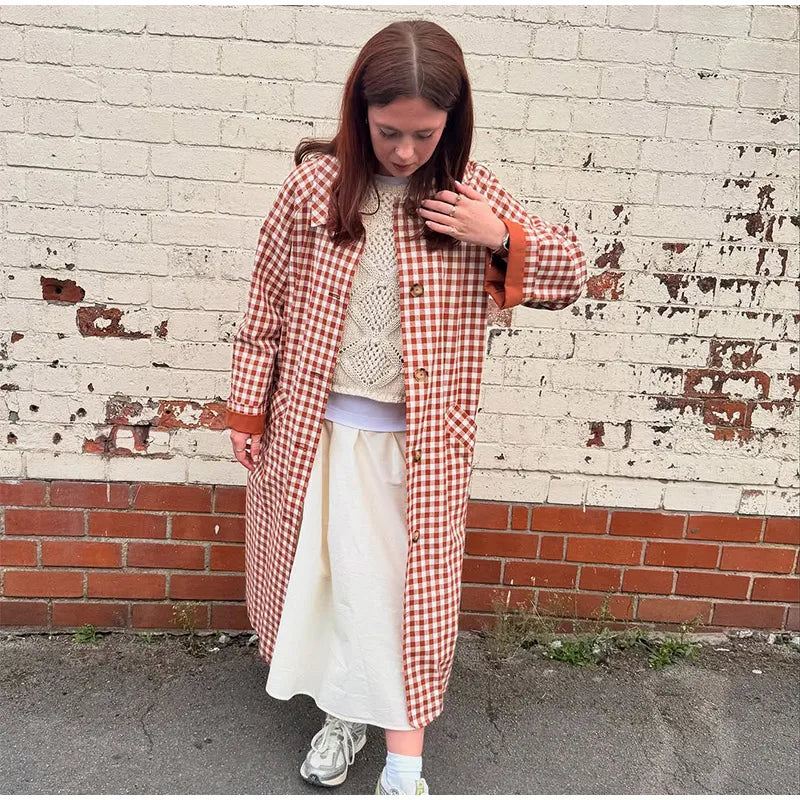 Person wearing a red and white checkered coat against a brick wall.