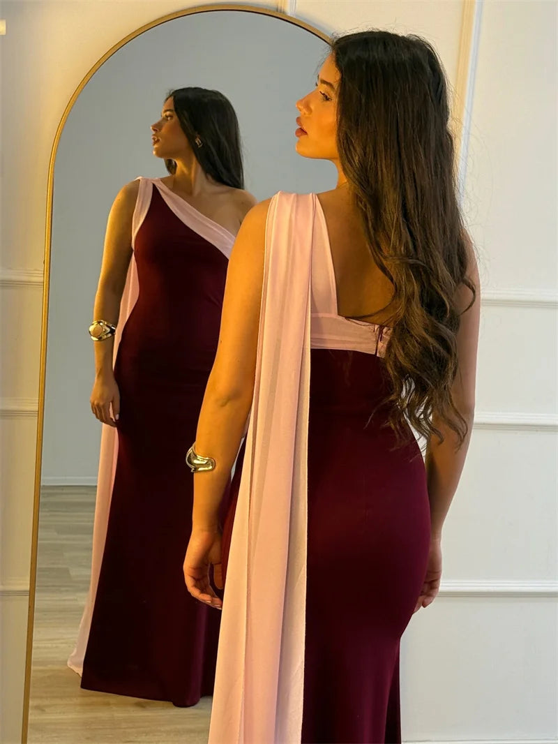 Woman in a burgundy dress with a pink scarf standing in front of a mirror.