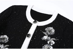 Close-up of the neckline and button detail on a black sequined knit cardigan.