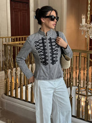 Model wearing the grey denim embroidered jacket with white pants.